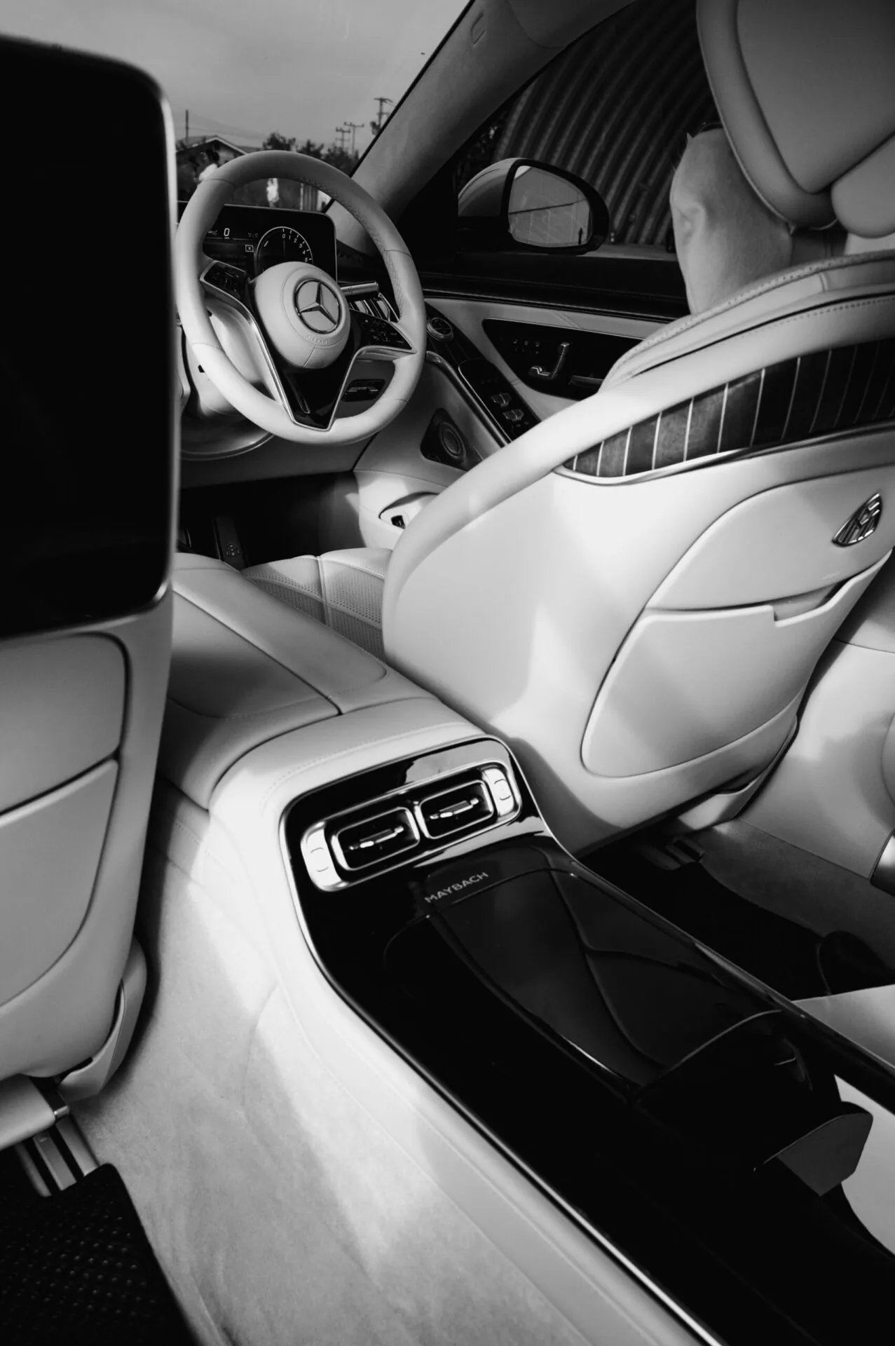 Black and white shot of a luxury Mercedes supercar interior showing steering wheel and rear seating