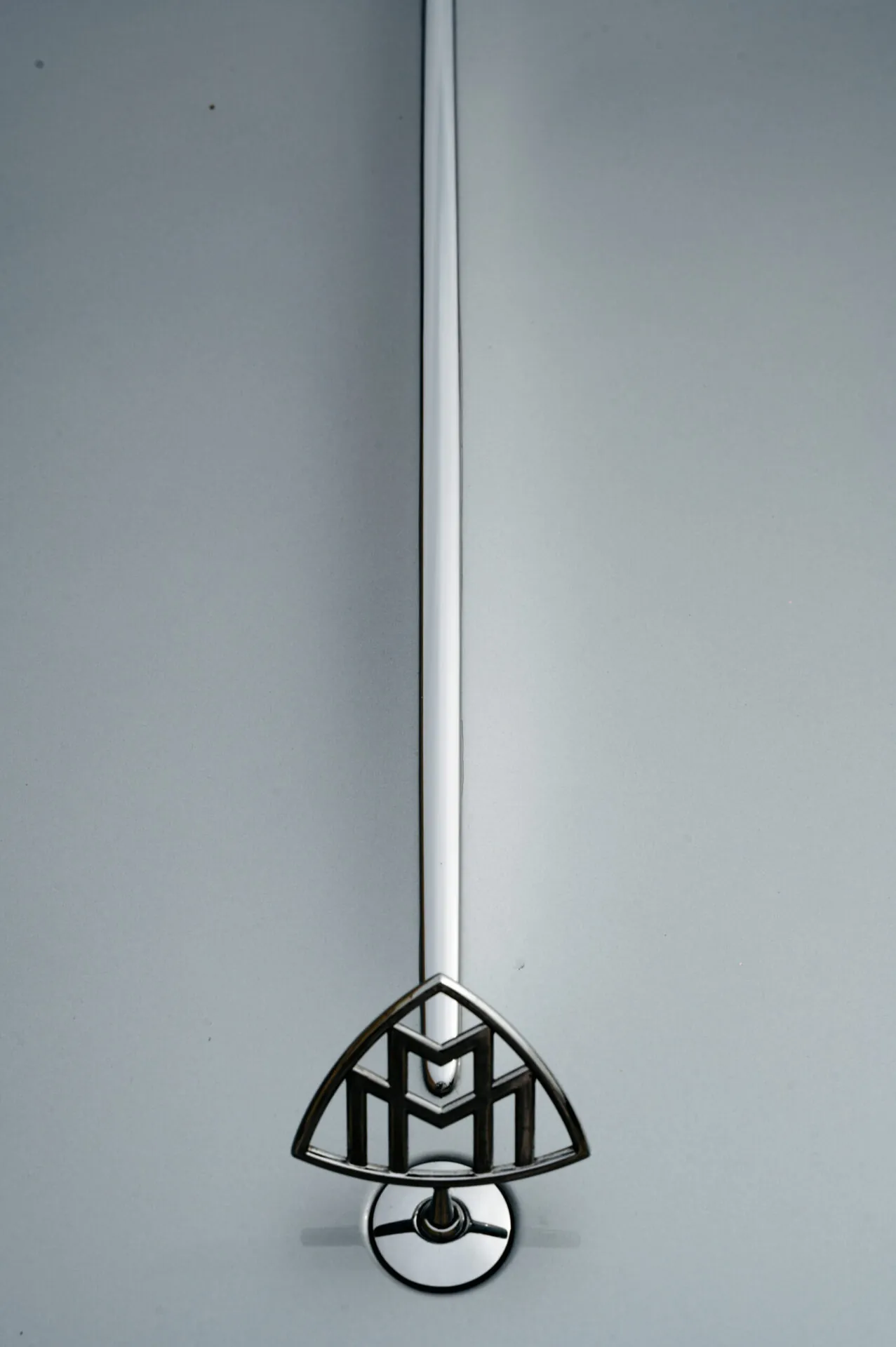 Close up of a Maybach luxury supercar hood ornament against a plain background