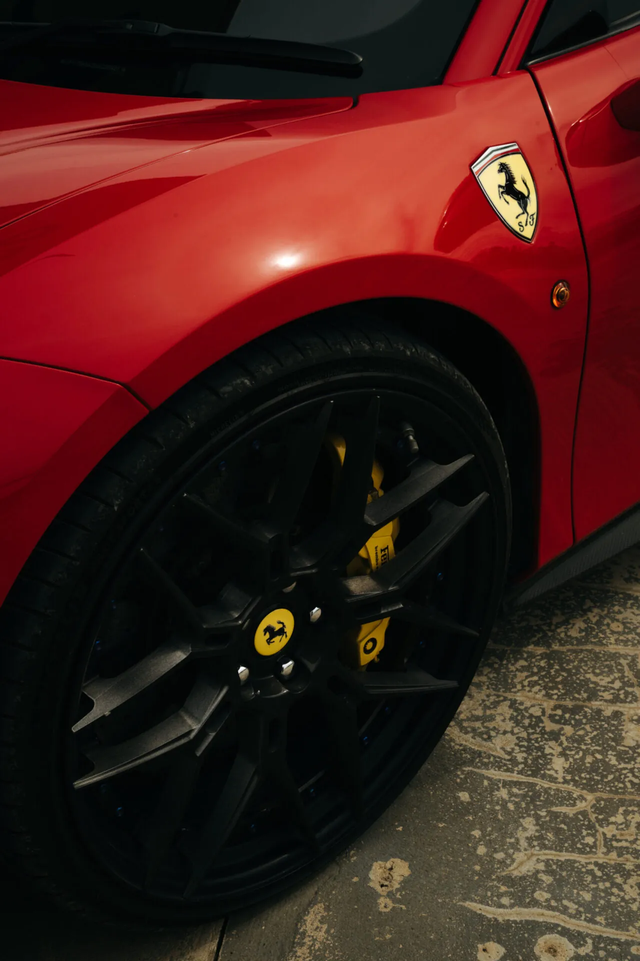 Close up of a red Ferrari supercar front wheel and logo detailing